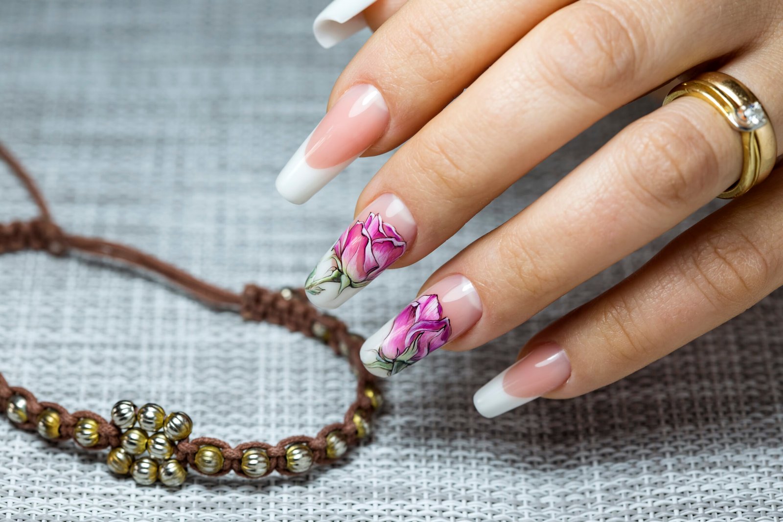 Beautiful multicolored flowers on a transparent lacquer on the nails on a gray decor