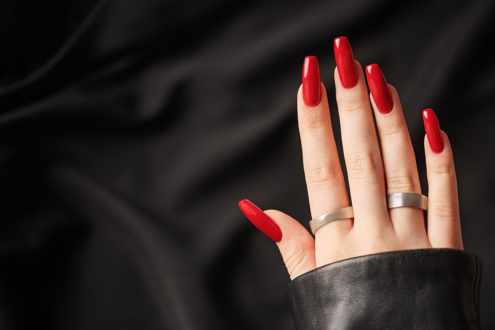 Hands of young girl with red  manicure on nails on black  background